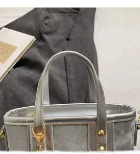 Close-up of a silver tote bag featuring gold metal rivets on grey suit fabric