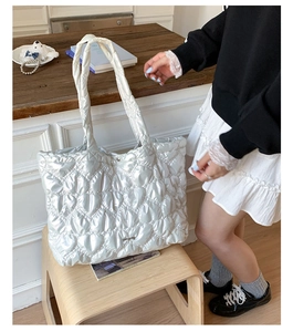 Detailed close-up of heart-shaped quilted stitching on metallic silver tote bag