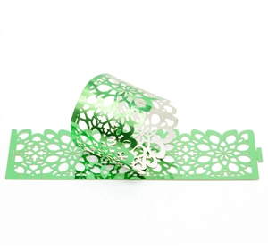 Detail of laser-cut green metallic paper napkin ring with intricate floral geometric patterns