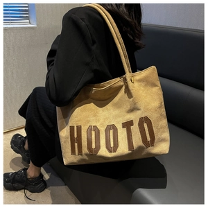 Detail of a large yellow suede tote bag with HOOTO letter patches on shoulder