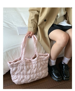 Lifestyle view of the pink quilted heart tote bag showing size and shoulder fit on a model