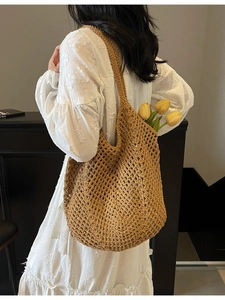 Brown woven straw tote bag with hollow mesh design shown on a model in a casual setting