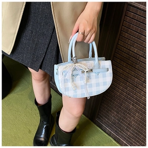 Detailed close-up of blue plaid mini bucket bag with lace bow and pearl charms