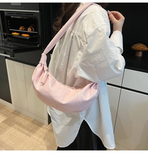 Detail of pink croissant bag with pleated texture and stylish knotted shoulder strap