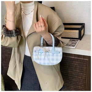 Detail of blue plaid bucket bag featuring pearl charms and white lace ribbon decoration