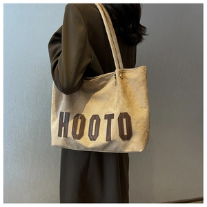 Detail of suede tote bag with HOOTO leather lettering and slender shoulder straps