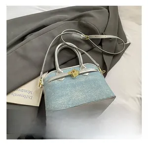 Detail showing light blue denim bucket bag with silver leather handles and gold lock buckle