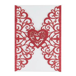 Close-up of laser-cut red glitter wedding invitation with intricate floral heart pattern