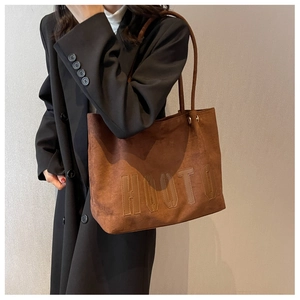 Close-up of HOOTO embossed lettering on dark brown suede tote bag with shoulder strap