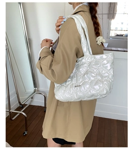 Detail of white quilted heart pattern tote bag with pearlescent finish and metal logo