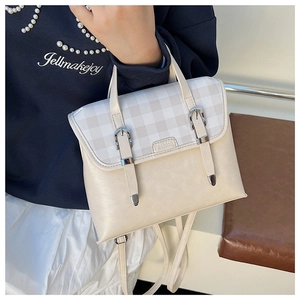 Detail of British style cream backpack featuring a plaid flap and metal fashion logo