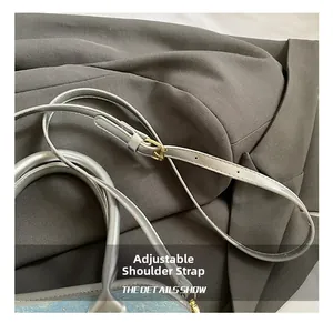 Detail showing adjustable silver leather strap and gold metal buckle on denim bucket bag
