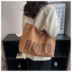 Macro detail of brown suede tote bag with HOOTO leather lettering and soft matte texture