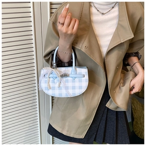 Detail of blue and white plaid mini bucket bag with pearl lace charm and metal clasp