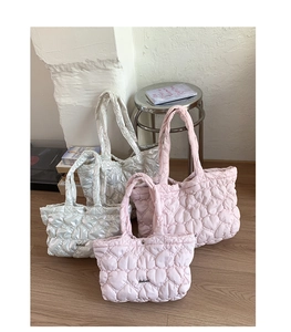 Detailed view of quilted heart pattern tote bags in metallic silver and soft pink shades