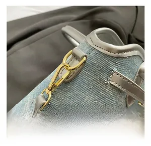 Close-up of golden metal hook and denim fabric with silver studs on a bucket bag