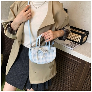 Detail of light blue plaid bucket bag featuring pearl and lace bow decoration