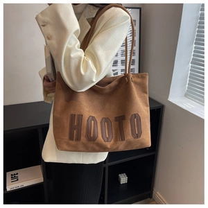 Detailed side view of the large brown suede tote bag with HOOTO leather embroidery