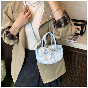 Detail of blue plaid bucket bag with pearl lace bow and slim shoulder strap on model