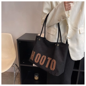 Canvas tote bag with Hooto patch worn with white blazer and black pleated skirt