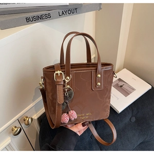 Detail of a brown PU leather bucket bag with gold hardware and a cherry charm