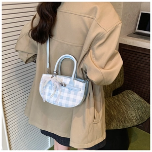 Detail of light blue gingham bucket bag with pearl and lace bow charm on model