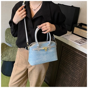 Detail of light blue tweed bucket bag with silver leather handle and golden padlock