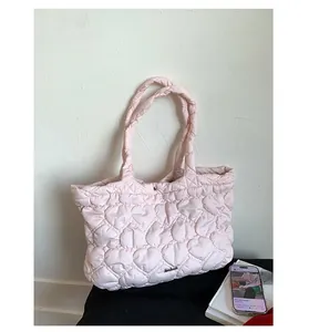 Detailed close-up of pink quilted tote bag with heart patterns and metallic logo