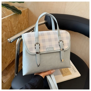 Detail of light blue plaid flap and Fashion label on British style retro satchel bag
