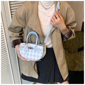 Detail of blue gingham bucket bag with white lace bow and elegant pearl charm detail