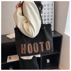 Detail of black tote bag with brown HOOTO lettering and spacious minimalist design
