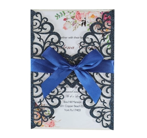 Detailed laser-cut wedding invitation with navy glitter cover and blue satin bow decoration