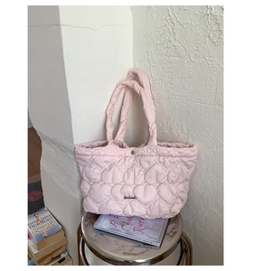 Detail of light pink quilted tote bag with heart patterns on a metal stool