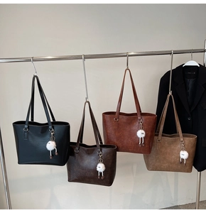 Row of textured leather tote bags in four colors with plush bear charms on display