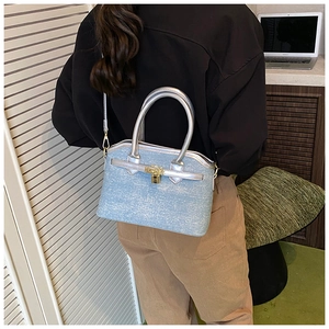Detail of light blue denim bucket bag with gold padlock and slim silver handles