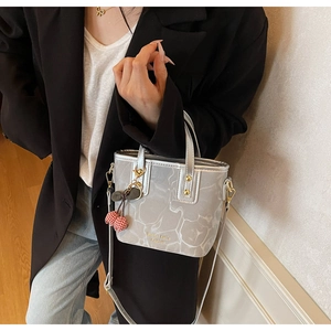 Detail of silver marble bucket bag featuring red cherry charm and gold lettering