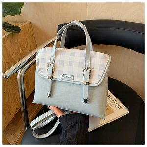 Light blue-grey satchel bag with checkered flap shown on a black leather seat