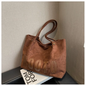 Detail of dark brown suede tote bag with HOOTO letter patch and slim shoulder straps