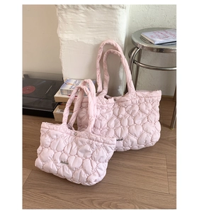 Detail of pink heart-quilted tote bags in two sizes with small metal logo on satin fabric