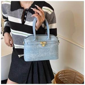 Detail of light blue denim bucket bag featuring signature gold lock and leather strap