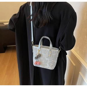 Detailed back view of a grey marble pattern bucket bag with a cherry pendant accessory