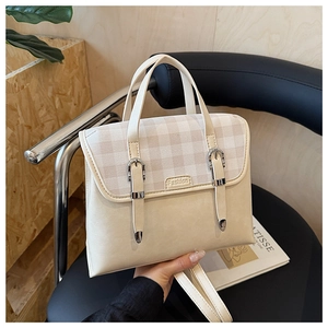 Detail of cream white handbag with checkered flap and buckle straps on a modern black chair