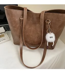 Detail of soft brown faux leather tote bag with long handles and plush charm accessory