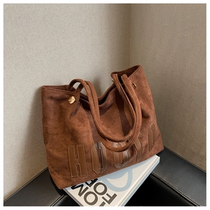 Detail of dark brown matte suede tote bag with HOUYO lettering and gold metal rings