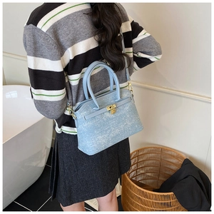 Detailed back view of a light blue textured bucket bag with gold hardware and strap