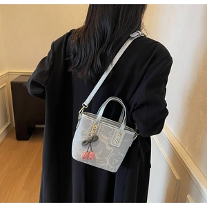 Silver marble pattern bucket bag with cherry charm worn over a classic black coat