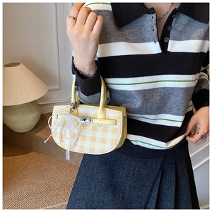 Close-up of yellow checkered bucket bag with pearl lace bow charm and silver lock
