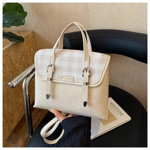 Detail of British style cream backpack featuring checkered flap and metallic buckle accents