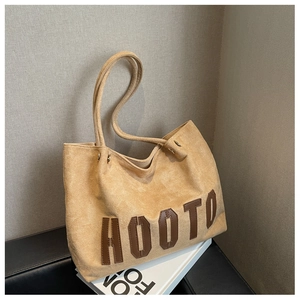 Close-up of beige suede tote bag featuring brown HOOTO letter patch and fine stitching
