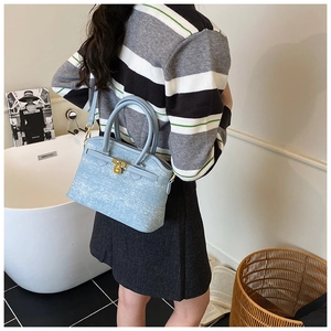 Detailed view of light blue denim bucket bag with gold hardware on a model back